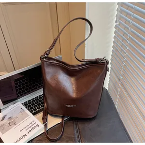 Détail d'un sac cabas en cuir marron foncé avec texture vintage et lettrage de mode