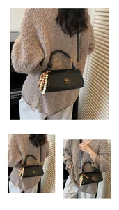 Detail of black crossbody bag featuring a golden twist lock and unique beaded charm