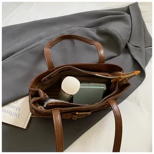 Vue de dessus de l'intérieur spacieux d'un sac marron avec poche zippée et cosmétiques