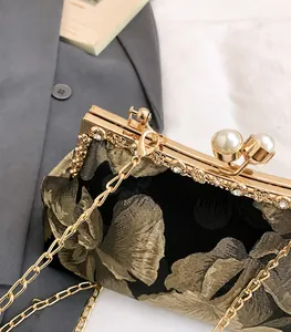 Détail d'un sac de soirée vintage avec broderie florale dorée et fermoir en perles