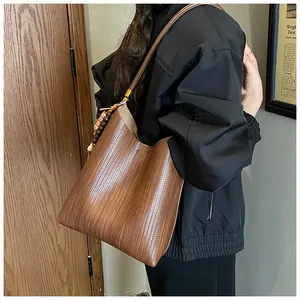 Gros plan d'un sac cabas en cuir tressé marron foncé avec un pendentif perlé vintage