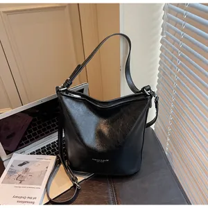 Gros plan du sac seau en cuir noir avec boucle métallique et détails texturés
