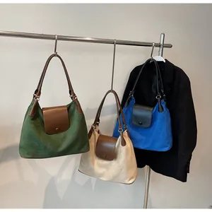 Three large tote bags in green, cream and blue hanging on a metal rack