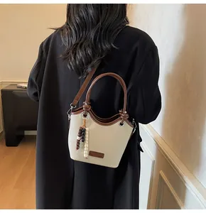 Détail d'un sac seau rétro avec pendentif en perles porté par un mannequin en blazer