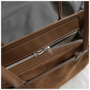Detailansicht der braunen Wildledertasche mit Lederbesatz und silbernem Reißverschluss