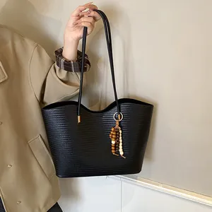 Minimalist black woven tote bag with wooden bead charm and long shoulder straps