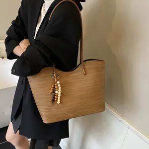 Brown woven tote bag with leather strap and decorative wood bead tassel for women