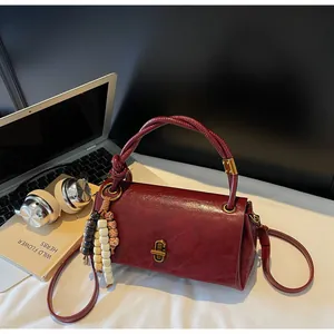 Detail of burgundy leather handbag with woven handle and vintage gold twist lock