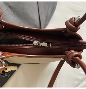 Détail du sac seau en toile avec bordure en cuir marron et fermeture éclair sécurisée