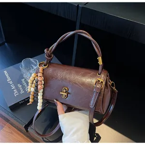 Detail view of brown leather handbag with gold twist lock and colorful wooden bead charms