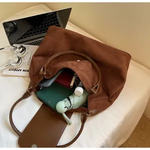 Top view of large brown tote bag interior filled with tablet, umbrella and wallet
