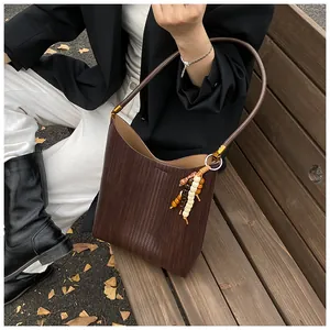 Détail d'un sac seau tressé marron avec perles en bois et finitions dorées