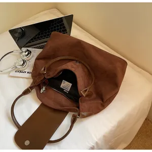 Detail of soft brown suede tote bag featuring internal brand tag and zipper closure