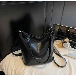 Détail du sac seau en cuir ciré noir avec boucles en métal argenté et texte du logo