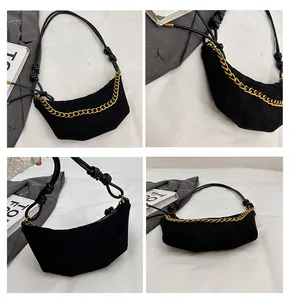 Detalle de bolso medialuna negro mate con cadena dorada y correa de nudo elegante
