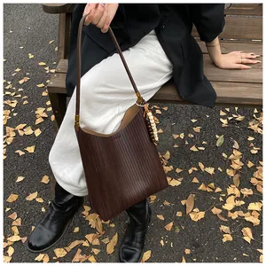 Détail d'un sac cabas tissé marron foncé avec pendentif en perles de bois au décor d'automne