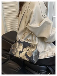 Détails de la broderie florale, du fermoir perle et du cadre strass sur ce sac de soirée
