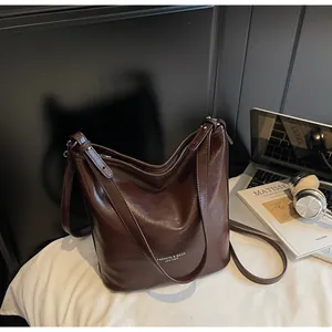 Gros plan sur le sac cabas en cuir poli marron foncé avec boucle métallique élégante
