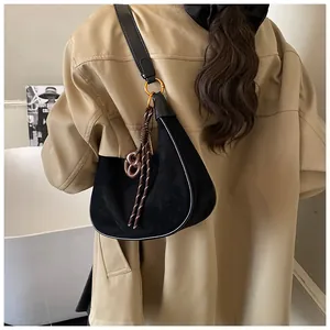 Detail of black suede hobo bag with gold ring hardware and unique pretzel charm
