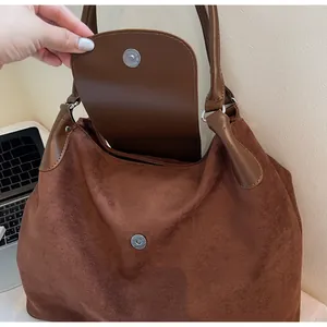 Close-up of the magnetic closure and suede texture on a brown tote handbag