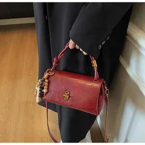Detail of vintage burgundy shoulder bag with knotted handle and colorful wooden beads