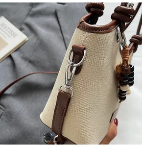 Vue détaillée du sac seau en toile avec garniture en cuir marron et breloque en bois