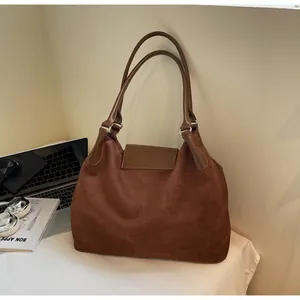 Brown matte suede and smooth leather tote bag styled on a desk with a laptop
