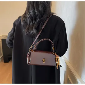 Detail view of a dark brown glossy leather crossbody bag with vintage gold metal lock