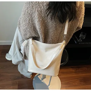 Détail d'un sac cabas en cuir beige minimaliste avec texte logo et bandoulière amovible