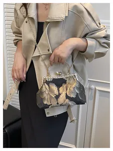 Détails de broderie florale vintage, monture en strass et fermoir perle sur sac de soirée