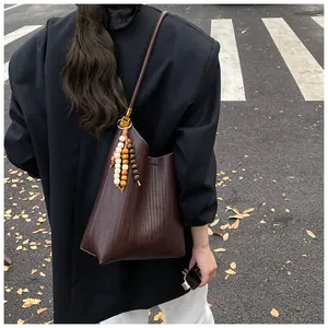 Vue de rue d'un grand sac seau tressé marron avec détail de glands en bois