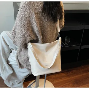 Modèle portant un grand sac cabas crème en cuir montrant la capacité pour le quotidien
