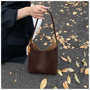 Détail du sac seau marron vintage avec texture embossée et breloque en perles perlées