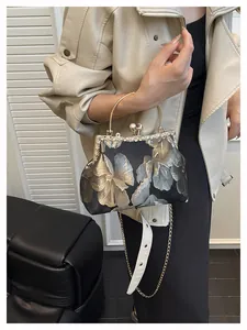 Détails de broderie florale avec fermoir perle et poignée en métal sur un sac à main noir