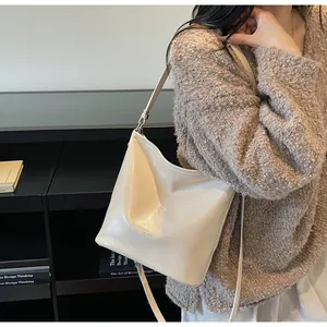 Détail du sac cabas en cuir crème avec texture subtile et bandoulière élégante
