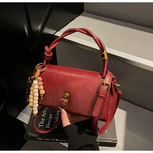 Detail of vintage burgundy leather handbag with twisted rope handle and beaded tassel