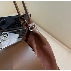 Detail of contrast textures on brown tote bag with suede body and leather trim accents