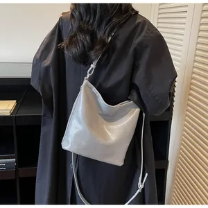 Détail du cabas en cuir gris brillant avec texte embossé et fines bandoulières