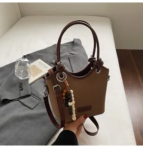 Gros plan du sac seau marron vintage avec pendentif en perles et bordure en cuir