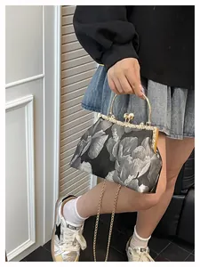 Détail du sac brodé vintage avec fermoir métallique, perle et bandoulière en chaîne