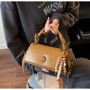 Close-up of brown vintage leather bag with unique knotted handle and golden metal lock