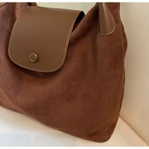 Detailed macro view of dark brown frosted suede texture and smooth leather flap on bag