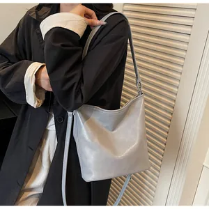 Détail d'un sac seau en cuir gris clair avec inscription mode et bandoulière réglable
