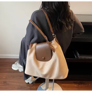 Detail of a large beige tote bag with brown leather straps shown on a model's shoulder