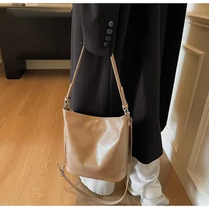 Détail d'un sac cabas en cuir marron clair avec texte blanc et bandoulière réglable