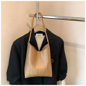 Détail d'un sac à bandoulière en cuir tressé marron clair avec boucles dorées