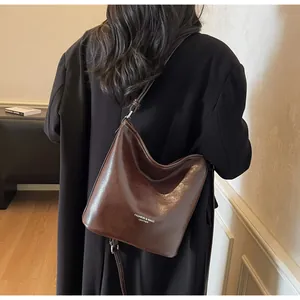 Détail du sac cabas en cuir marron foncé avec texte blanc et bandoulière réglable
