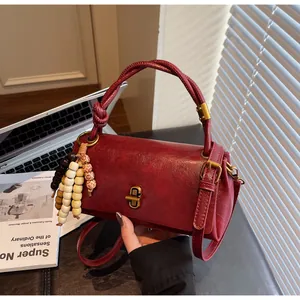 Close-up of wine red textured leather handbag with gold twist lock and beaded tassel
