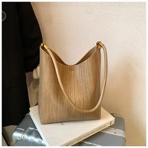 Gros plan du sac à bandoulière tressé kaki avec détails de boucle en métal doré