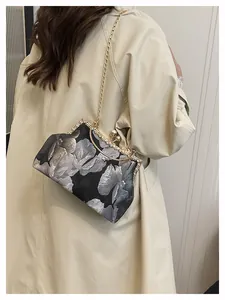 Détail de broderie florale vintage et chaîne dorée sur un sac à main de soirée chic